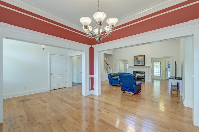 unfurnished living room with crown molding, light hardwood / wood-style flooring, and an inviting chandelier