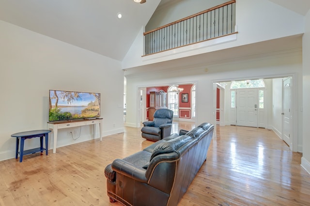 living room with high vaulted ceiling, an inviting chandelier, and light hardwood / wood-style floors