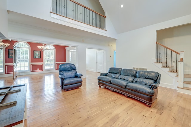 living room featuring light wood-type flooring, high vaulted ceiling, and an inviting chandelier