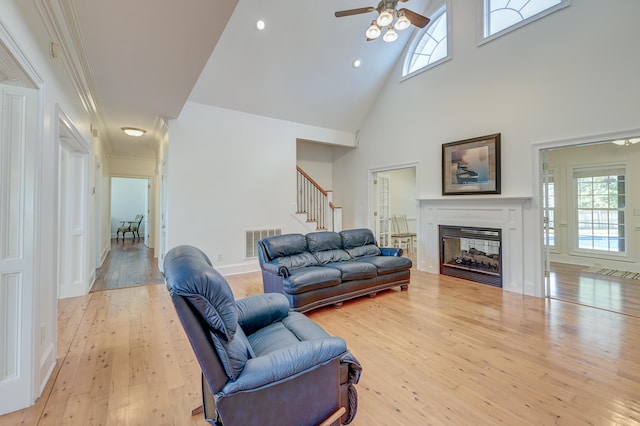 living room with plenty of natural light, ceiling fan, light hardwood / wood-style flooring, and high vaulted ceiling