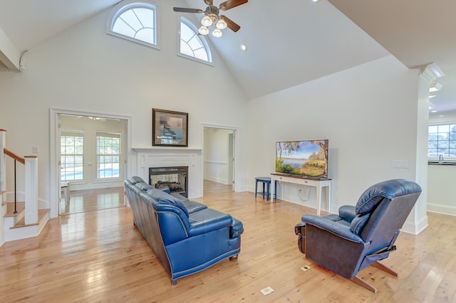 living room with light wood-type flooring, ceiling fan, high vaulted ceiling, and a healthy amount of sunlight