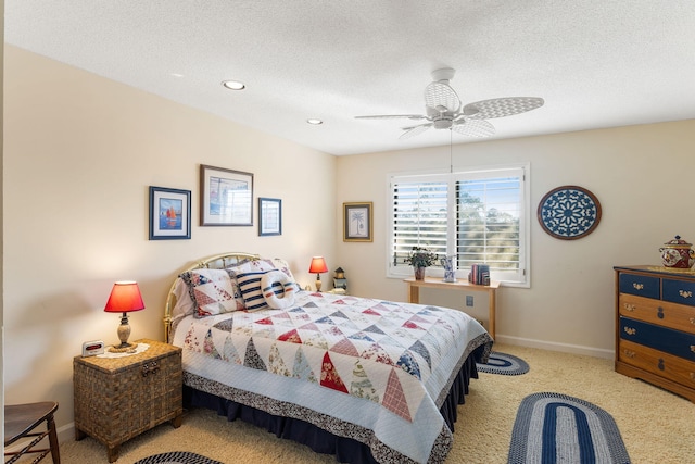 bedroom with ceiling fan, light colored carpet, and a textured ceiling