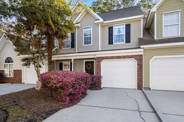 townhome / multi-family property featuring brick siding, an attached garage, and driveway