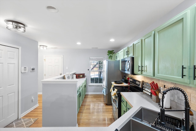 kitchen featuring a sink, stainless steel appliances, light wood-type flooring, and green cabinetry