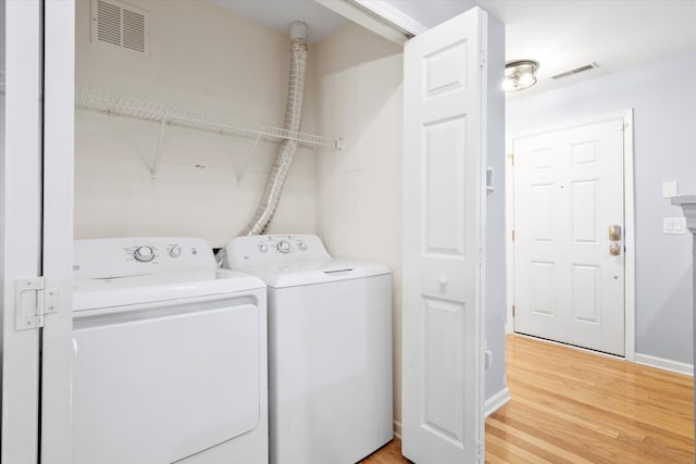 clothes washing area with independent washer and dryer, laundry area, light wood-style flooring, and visible vents