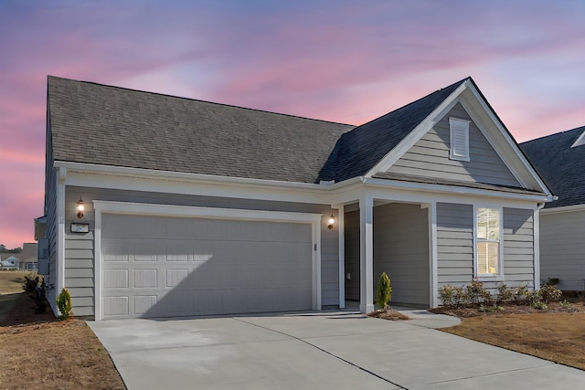 view of front of property featuring a garage, driveway, and a shingled roof