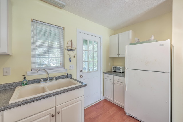 kitchen featuring white fridge, white cabinetry, and sink