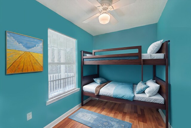 bedroom featuring multiple windows, hardwood / wood-style flooring, and ceiling fan