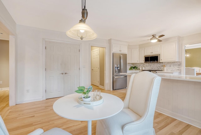 dining area featuring light wood-type flooring, a ceiling fan, and baseboards