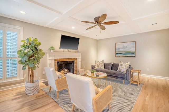 living area with light wood finished floors, coffered ceiling, a fireplace, and baseboards