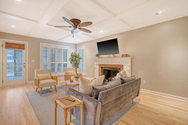 living area featuring light wood-type flooring, coffered ceiling, a fireplace, and baseboards