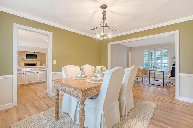 dining area with crown molding, light wood finished floors, and a notable chandelier