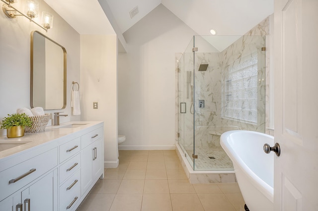 bathroom featuring a sink, a freestanding bath, vaulted ceiling, a marble finish shower, and double vanity