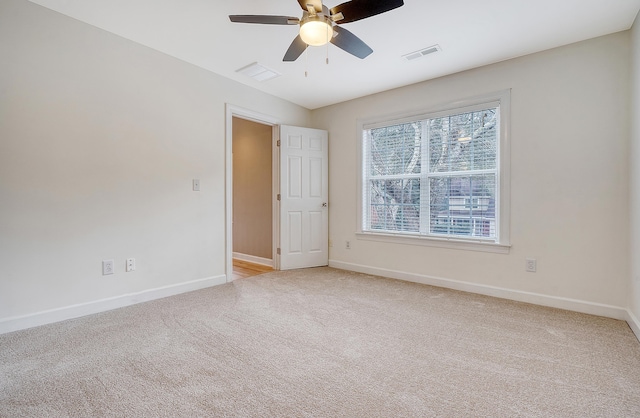 unfurnished room with light carpet, visible vents, baseboards, and ceiling fan