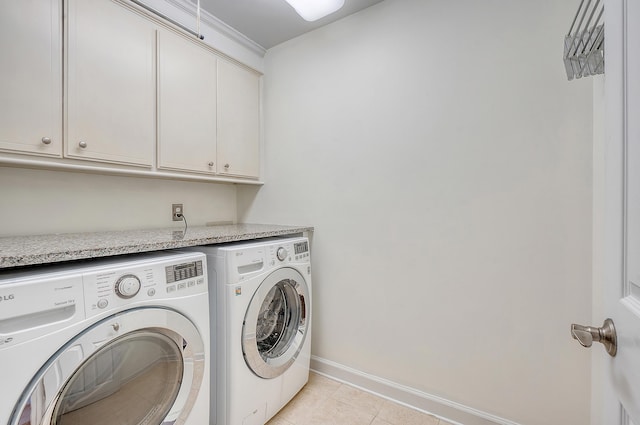 laundry area featuring washing machine and dryer, cabinet space, baseboards, and light tile patterned floors