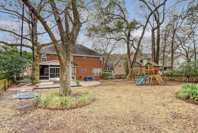 view of yard featuring a patio, a playground, a fenced backyard, and a sunroom