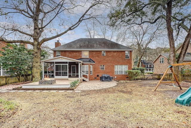 back of property featuring a sunroom, a fenced backyard, a chimney, and a playground