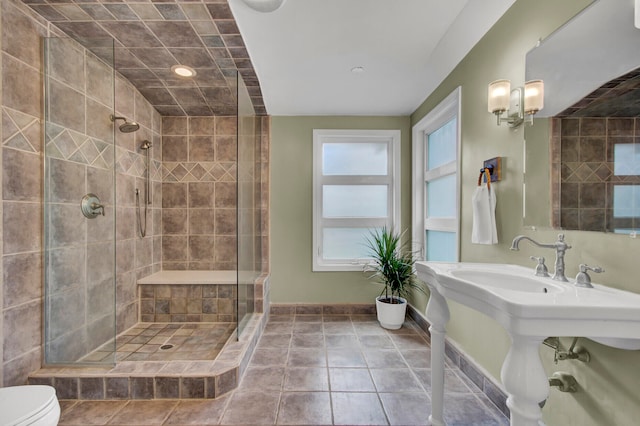 bathroom with tile patterned flooring, toilet, and a tile shower