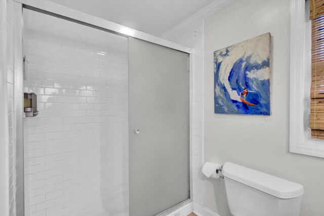 bathroom featuring an enclosed shower, toilet, and ornamental molding