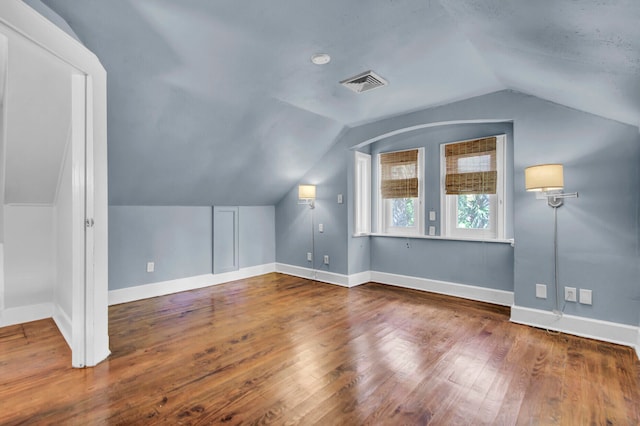 additional living space with hardwood / wood-style floors and vaulted ceiling