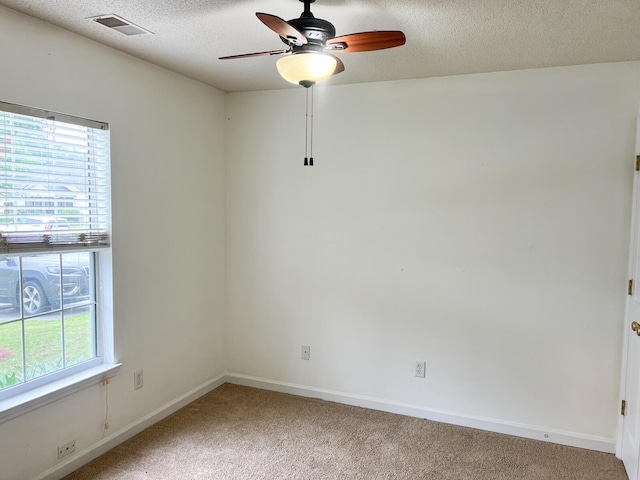 spare room featuring light colored carpet, ceiling fan, a textured ceiling, and baseboards
