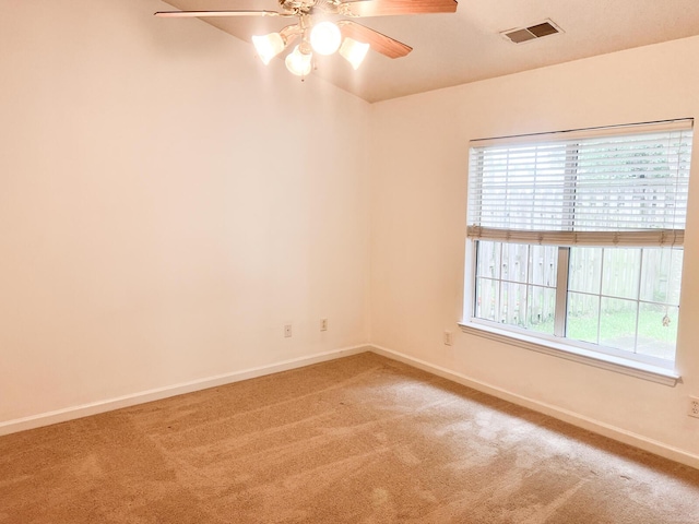 spare room featuring light colored carpet, baseboards, and ceiling fan