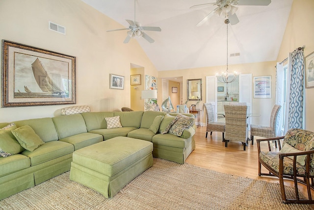 living room featuring light wood-type flooring, high vaulted ceiling, visible vents, and ceiling fan with notable chandelier