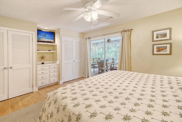 bedroom with access to exterior, visible vents, light wood finished floors, multiple closets, and a textured ceiling