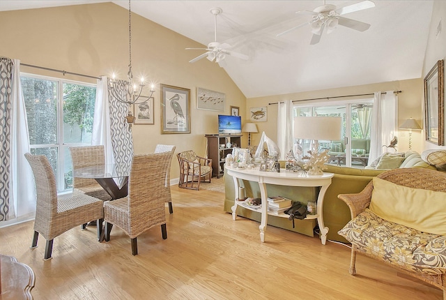 dining area featuring light wood finished floors, ceiling fan with notable chandelier, and high vaulted ceiling