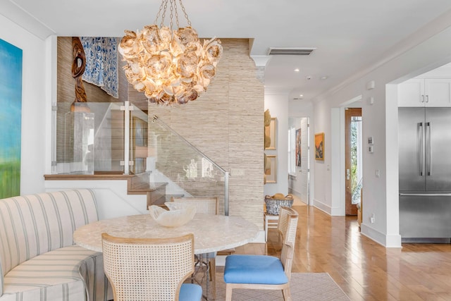 dining area featuring an inviting chandelier, light wood-type flooring, and crown molding