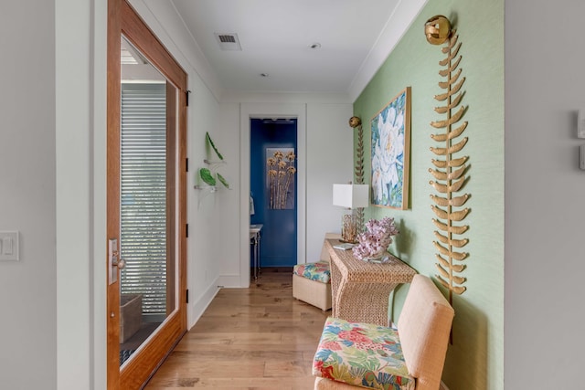 corridor featuring light hardwood / wood-style flooring, a healthy amount of sunlight, and crown molding