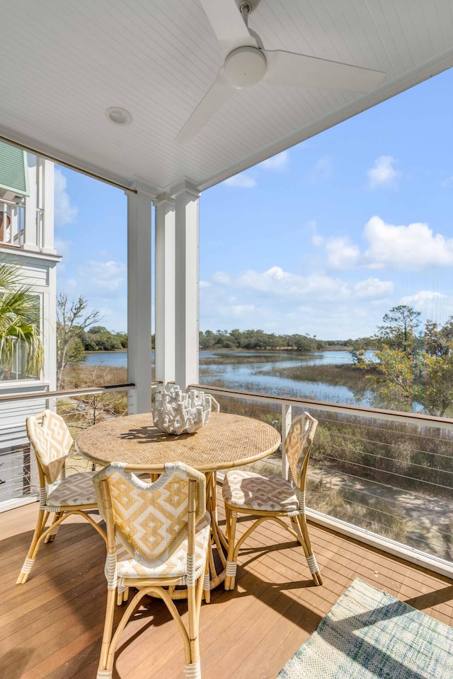 sunroom with ceiling fan and a water view