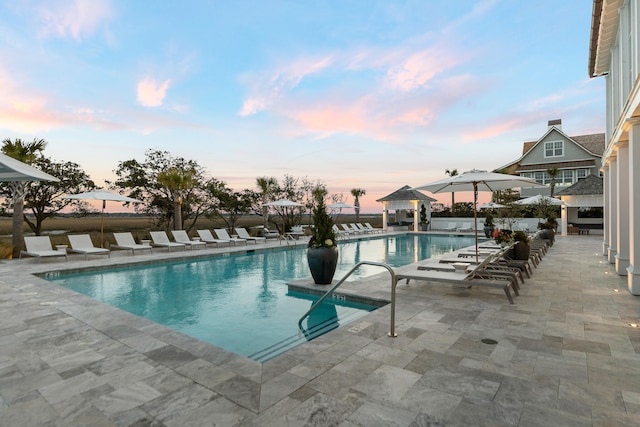 pool at dusk featuring a gazebo and a patio area