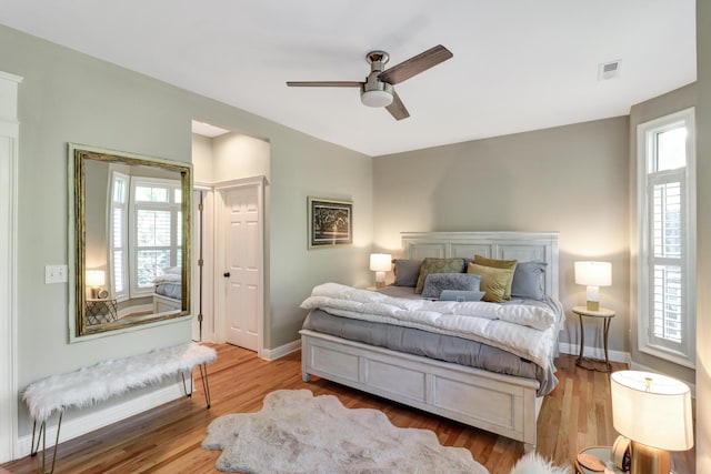 bedroom featuring multiple windows, ceiling fan, and light wood-type flooring