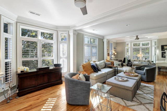 living room with ornate columns, ornamental molding, light wood-type flooring, and ceiling fan