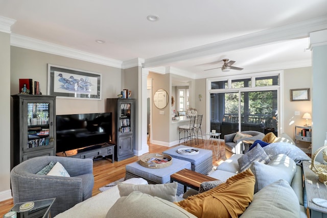 living room featuring crown molding, decorative columns, ceiling fan, and light wood-type flooring