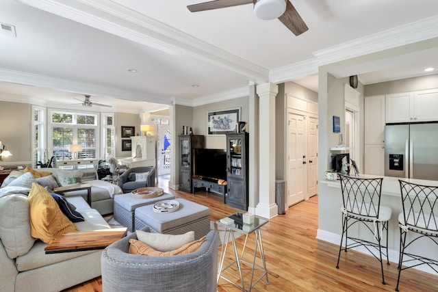 living room with ceiling fan, ornamental molding, decorative columns, and light wood-type flooring