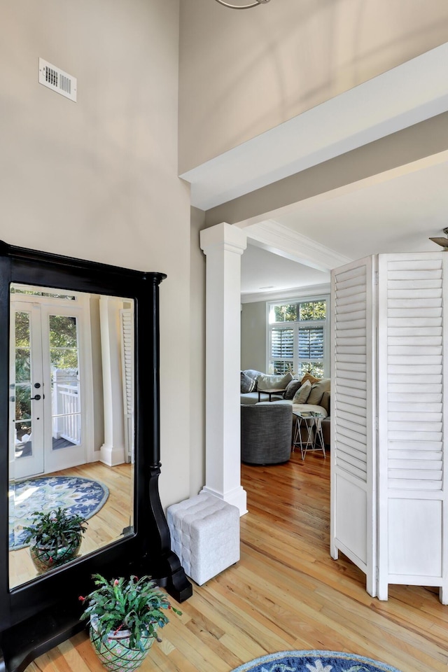 interior space with hardwood / wood-style flooring, french doors, and ornate columns