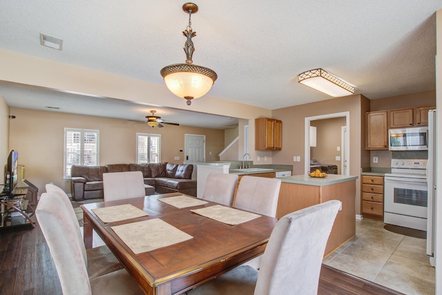 dining area featuring ceiling fan, visible vents, a textured ceiling, and wood finished floors