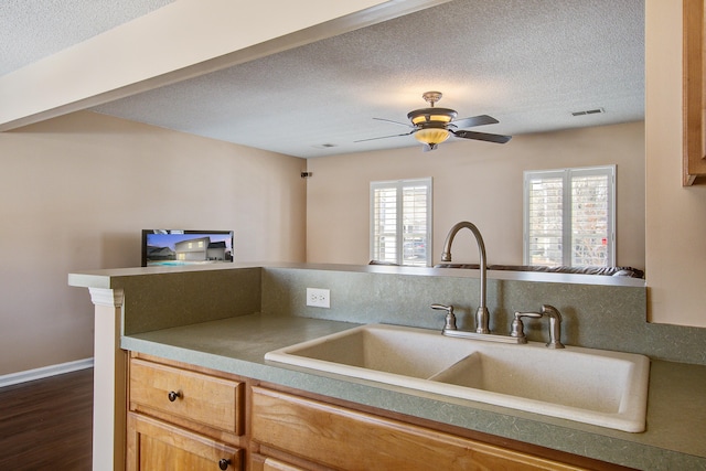 kitchen featuring ceiling fan, a textured ceiling, a sink, visible vents, and open floor plan