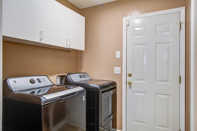 clothes washing area featuring separate washer and dryer and cabinet space