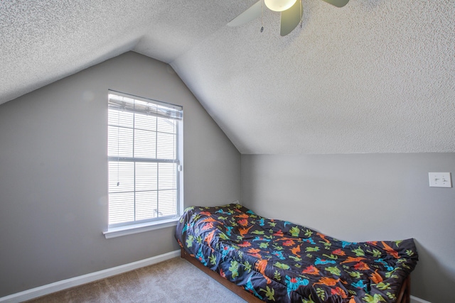 carpeted bedroom featuring vaulted ceiling, a textured ceiling, a ceiling fan, and baseboards