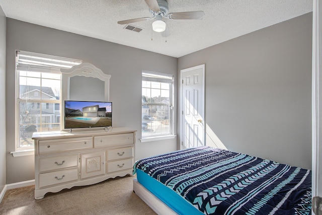 bedroom featuring light colored carpet, visible vents, a textured ceiling, and baseboards