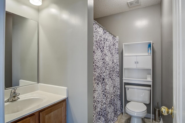 bathroom with visible vents, toilet, a textured ceiling, vanity, and tile patterned floors