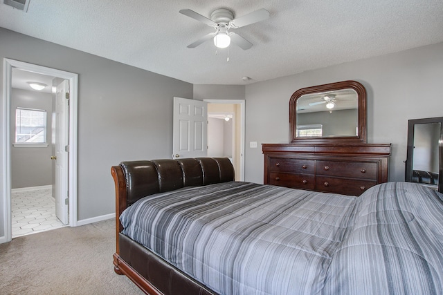 carpeted bedroom featuring ceiling fan, connected bathroom, baseboards, and a textured ceiling