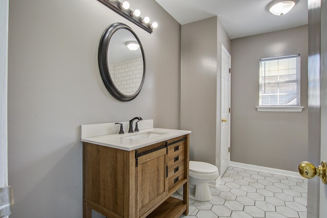 bathroom featuring toilet, vanity, baseboards, and tile patterned floors