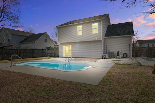 back of property at dusk featuring central AC unit, a patio area, a fenced backyard, and a fenced in pool