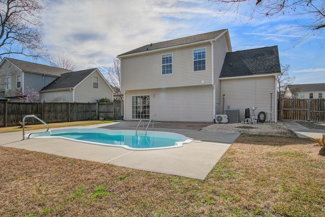 rear view of property with a fenced in pool, a patio area, a fenced backyard, and a lawn