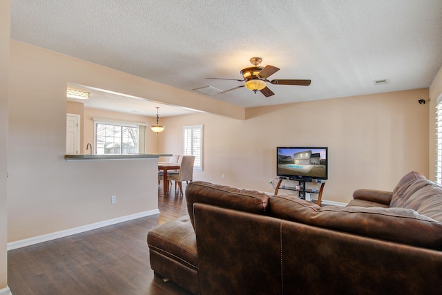 living area with baseboards, visible vents, ceiling fan, dark wood-style flooring, and a textured ceiling