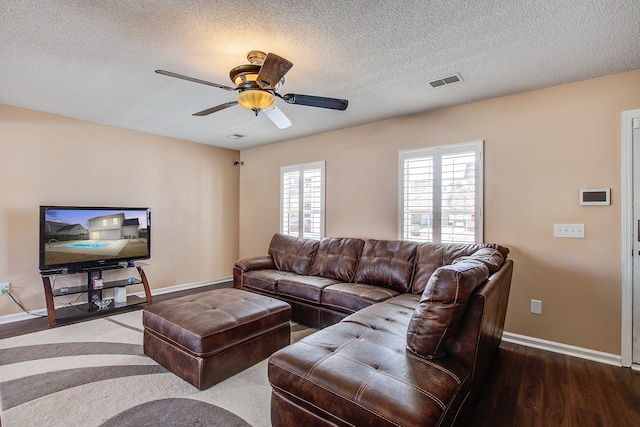 living area featuring visible vents, ceiling fan, a textured ceiling, wood finished floors, and baseboards